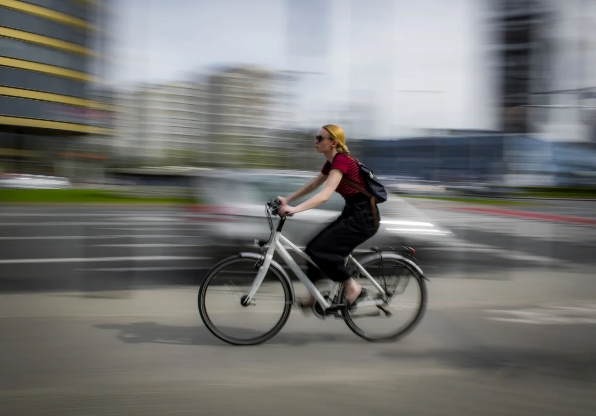 Woman in a red striped top and yellow headscarf riding through an intersection in motion blur